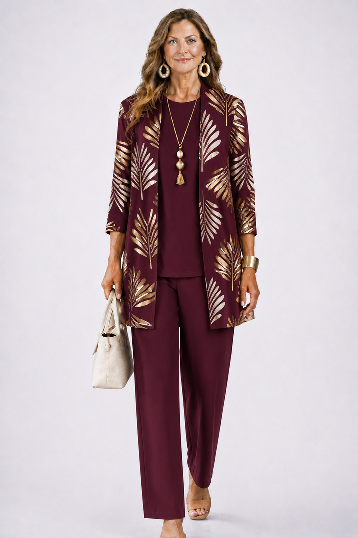 Femme en ensemble bordeaux, cardigan ouvert à feuilles dorées, haut uni et pantalon droit assortis. 6