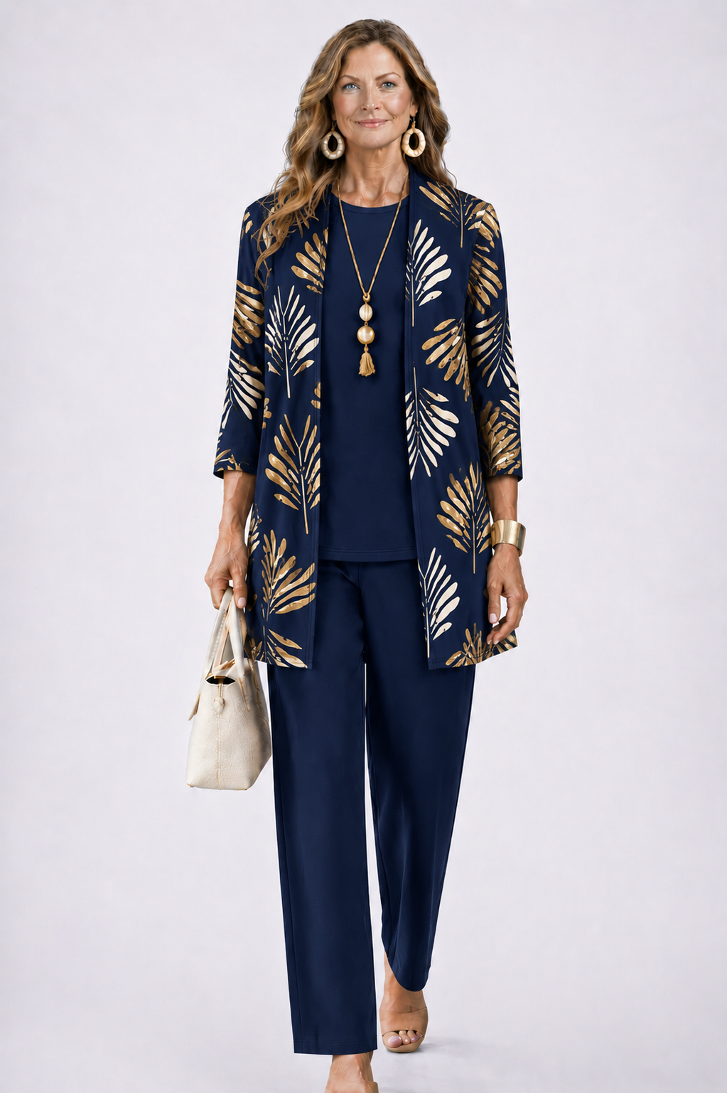 Femme en ensemble bleu marine, cardigan ouvert à feuilles dorées, haut et pantalon unis, collier à pompon. 7
