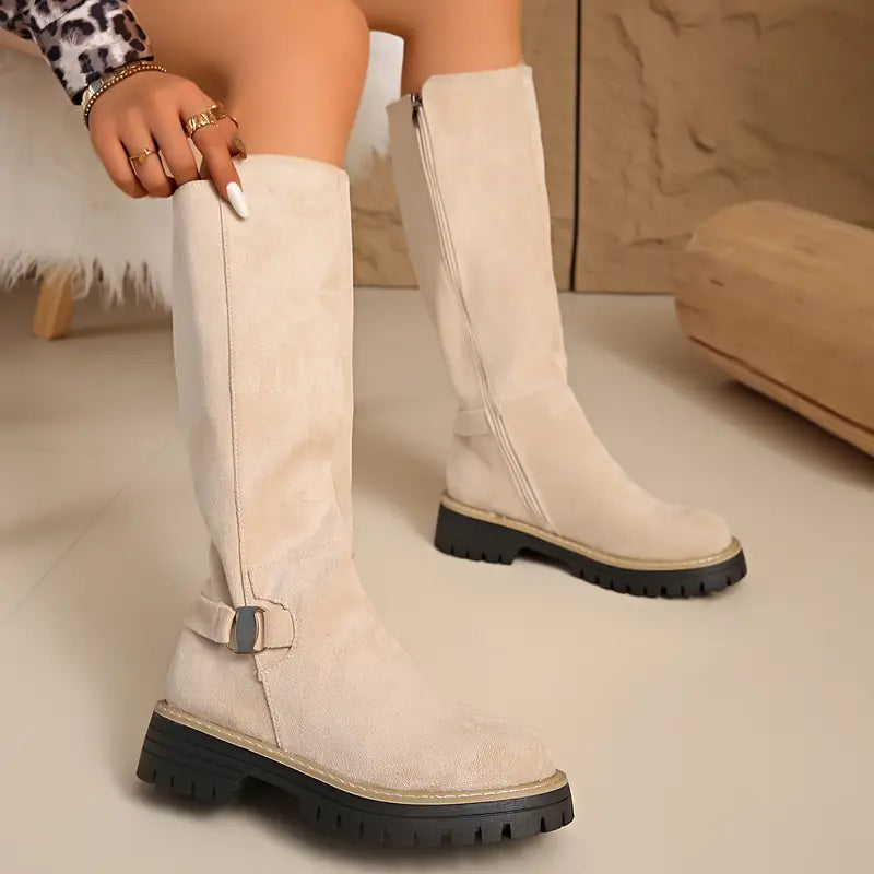 Bottes beige clair portées assise, montrant la boucle métallique sur la sangle et la fermeture éclair du côté intérieur. 9