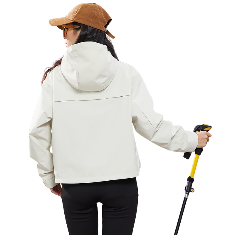 Vue de dos de la veste écru portée par une mannequin avec casquette, montrant la capuche et la couture horizontale du dos. 5