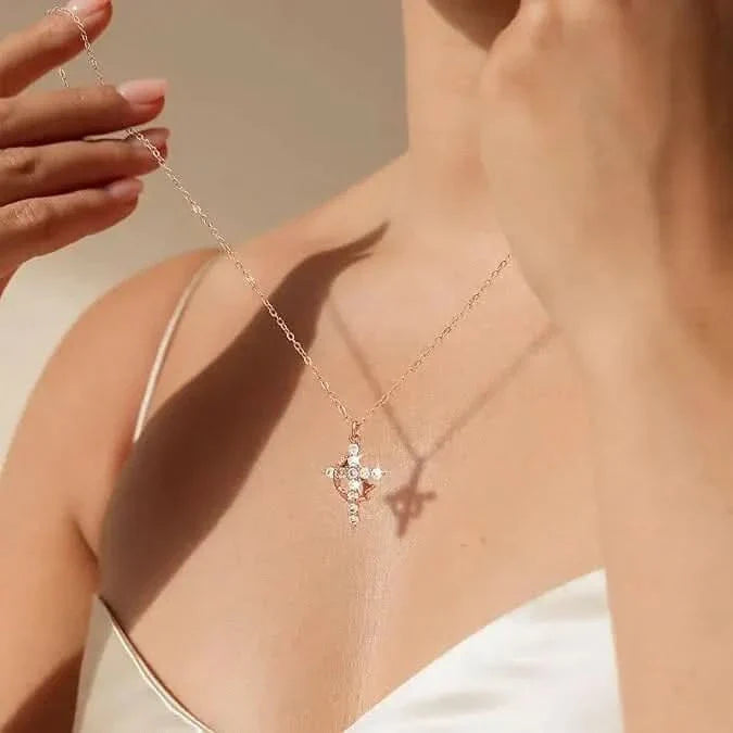 Femme tenant la chaÃ®ne d'un collier dorÃ© dont la croix ornÃ©e de petites pierres brille sur sa peau, ombre portÃ©e visible. 1