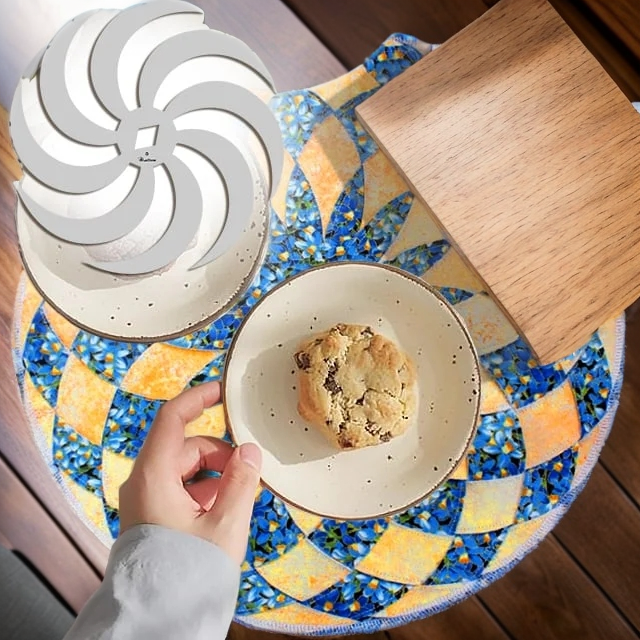 Set de table en patchwork bleu fleuri et orangé, avec une assiette portant un cookie, une main qui la saisit et le gabarit en spirale. 16