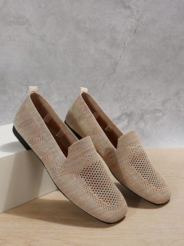 Paire beige en maille ajourée posée en appui sur un bloc blanc, languette de talon et semelle noire visibles. 7