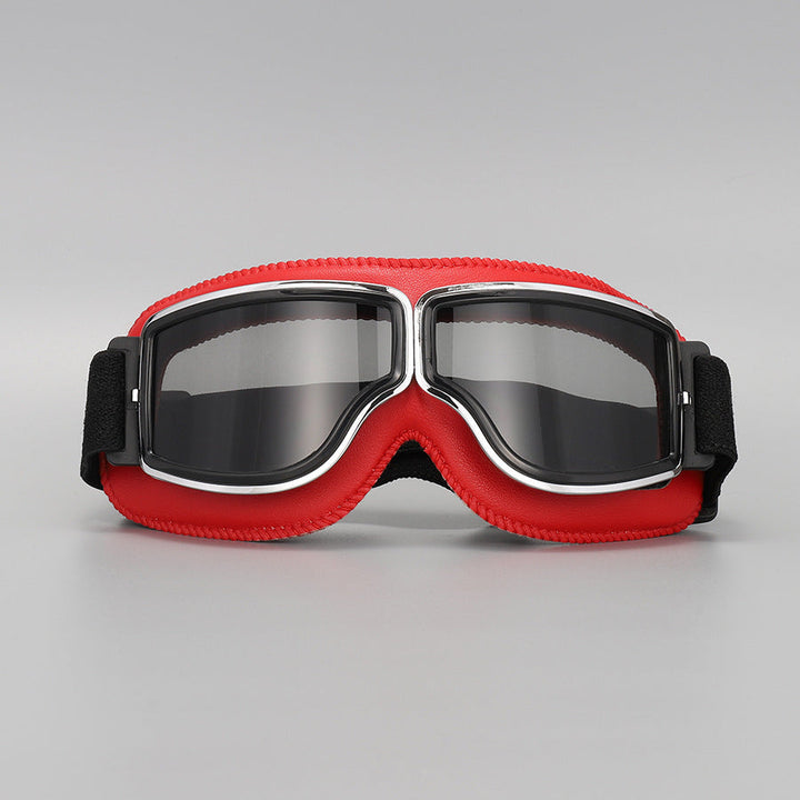 Lunettes à contour rouge vif avec verres fumés gris, monture chromée et sangle élastique noire, sur fond gris. 11