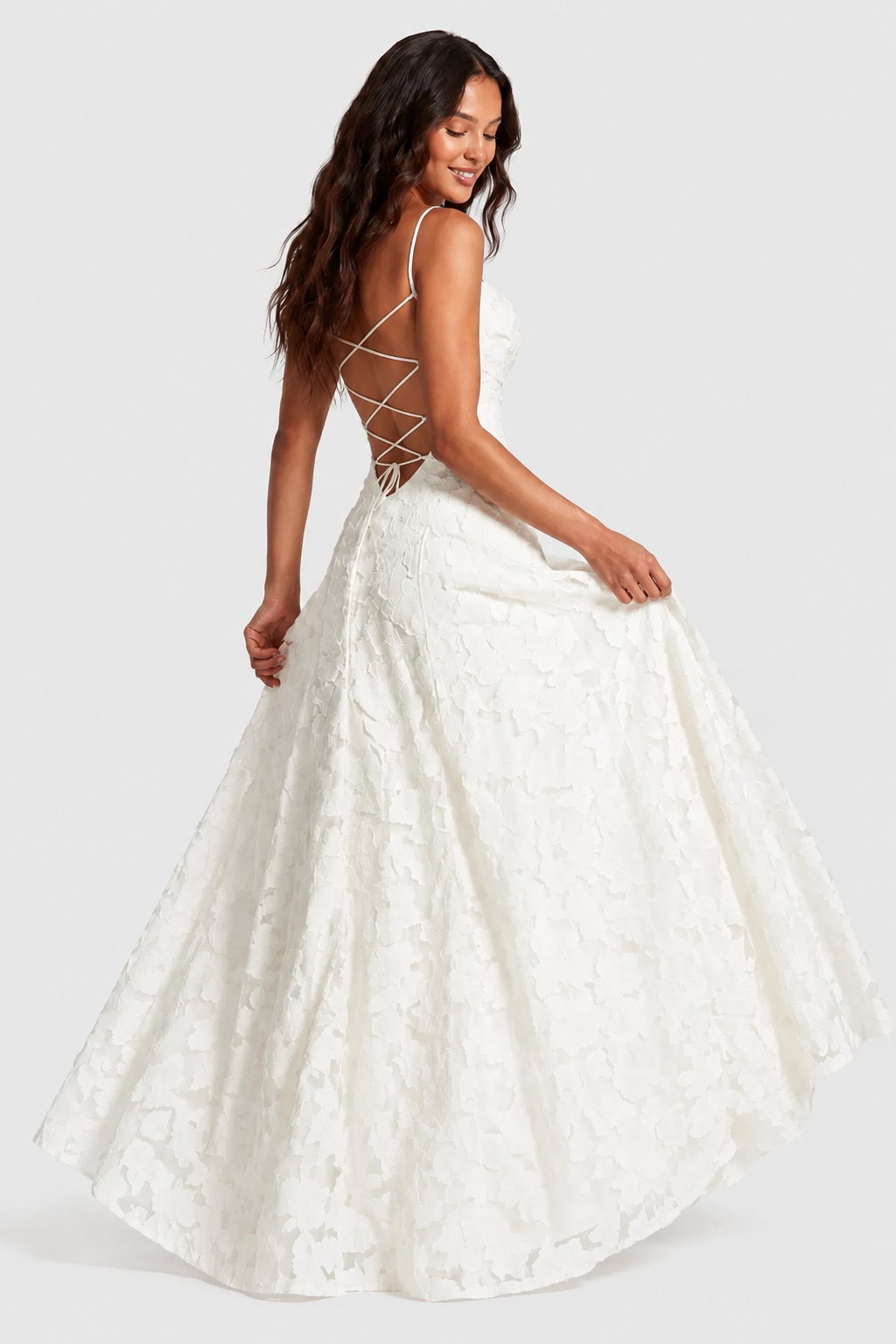 Robe blanche en dentelle florale vue de dos, laçage croisé sur le dos nu, mannequin en mouvement soulevant la jupe ample. 8