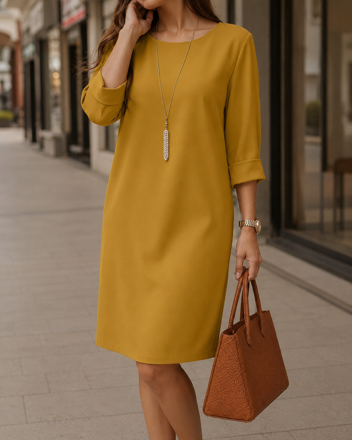 Robe moutarde droite à manches retroussées, portée en ville avec un sac cabas marron et un long pendentif 7