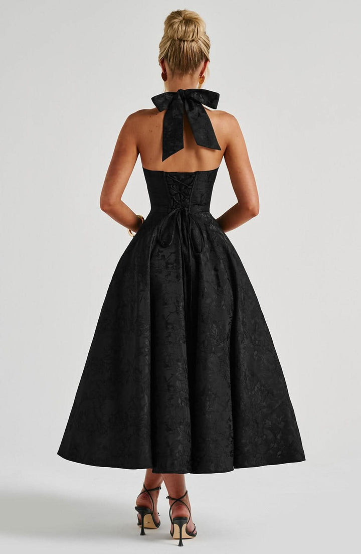 Dos de la robe noire, avec nœud au cou, dos ouvert, laçage corset et jupe évasée jusqu'aux mollets. 14