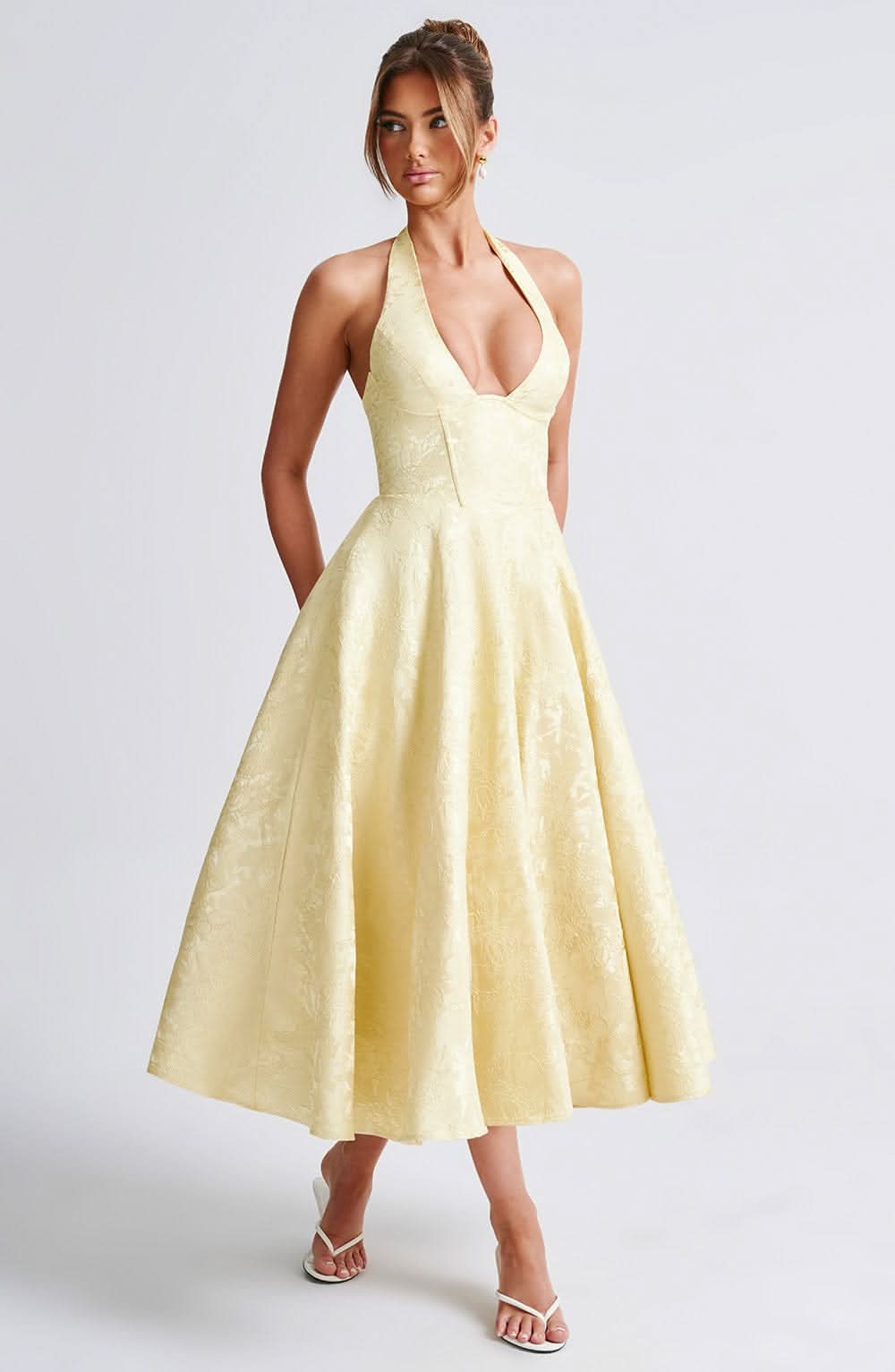 Robe jaune pâle à motif floral jacquard portée de face, col licou plongeant, taille corsetée et jupe évasée mi-longue. 4