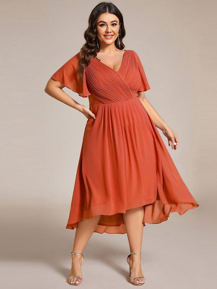 Robe orange terracotta portée par une mannequin grande taille, main sur la hanche, jupe ample asymétrique 97