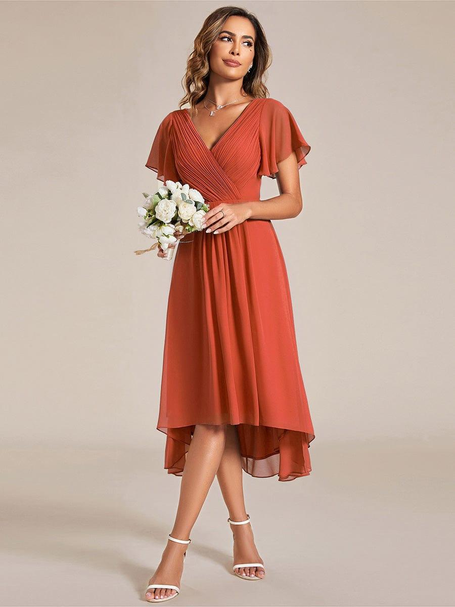 Robe orange terracotta portée avec un bouquet de fleurs blanches, mannequin regardant sur le côté, jupe asymétrique 95