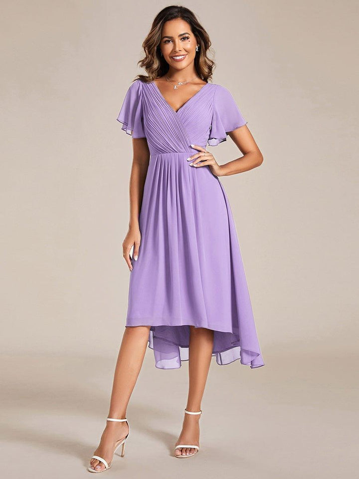 Robe lavande portée de face par une mannequin, main sur la hanche, buste plissé croisé et ourlet asymétrique 100