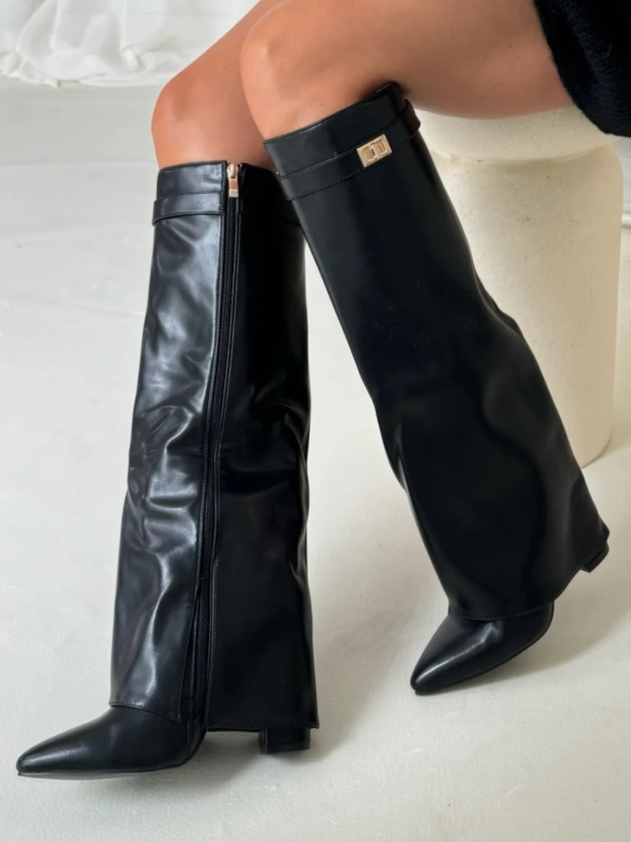 Bottes hautes noires en simili cuir brillant portées assise, zip latéral et boucle dorée sur la sangle visibles. 10