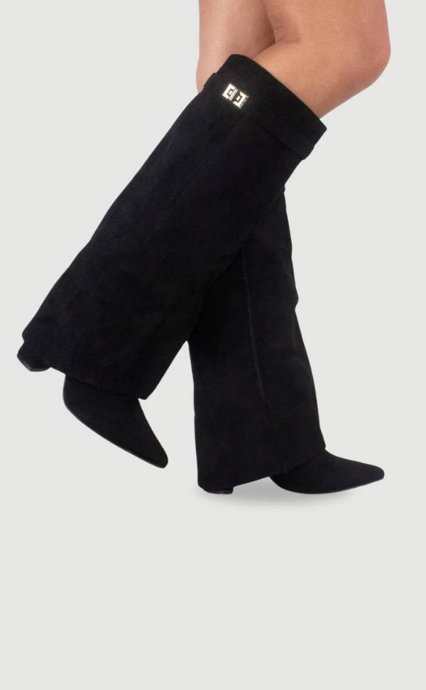 Bottes noires en daim portées en mouvement sur fond gris uni, boucle dorée à la sangle et bouts pointus. 12