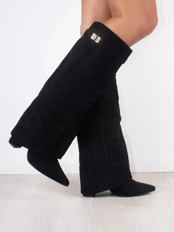 Bottes hautes noires en daim portées en marchant, vues de trois quarts avec la boucle dorée et le zip latéral visibles. 2