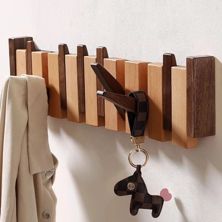 Gros plan sur le porte-manteau mural en bois bicolore, avec un porte-clés à cheval accroché et un manteau beige suspendu. 3