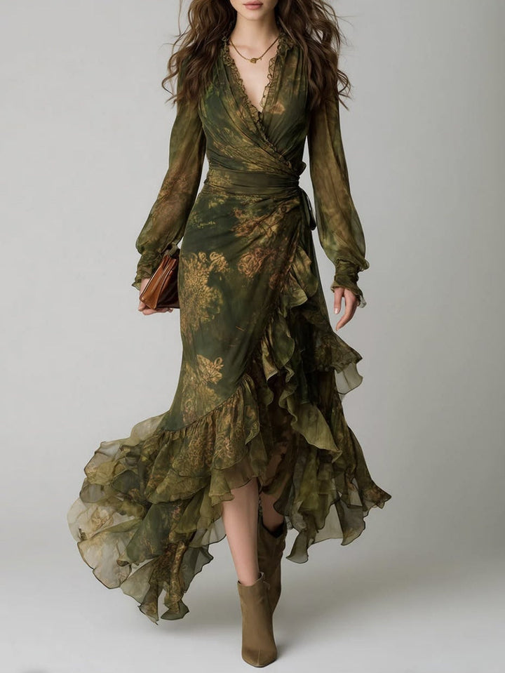 Femme portant la robe portefeuille verte à fleurs dorées, vue de face en pied, avec volants asymétriques, bottines et pochette marron. 1