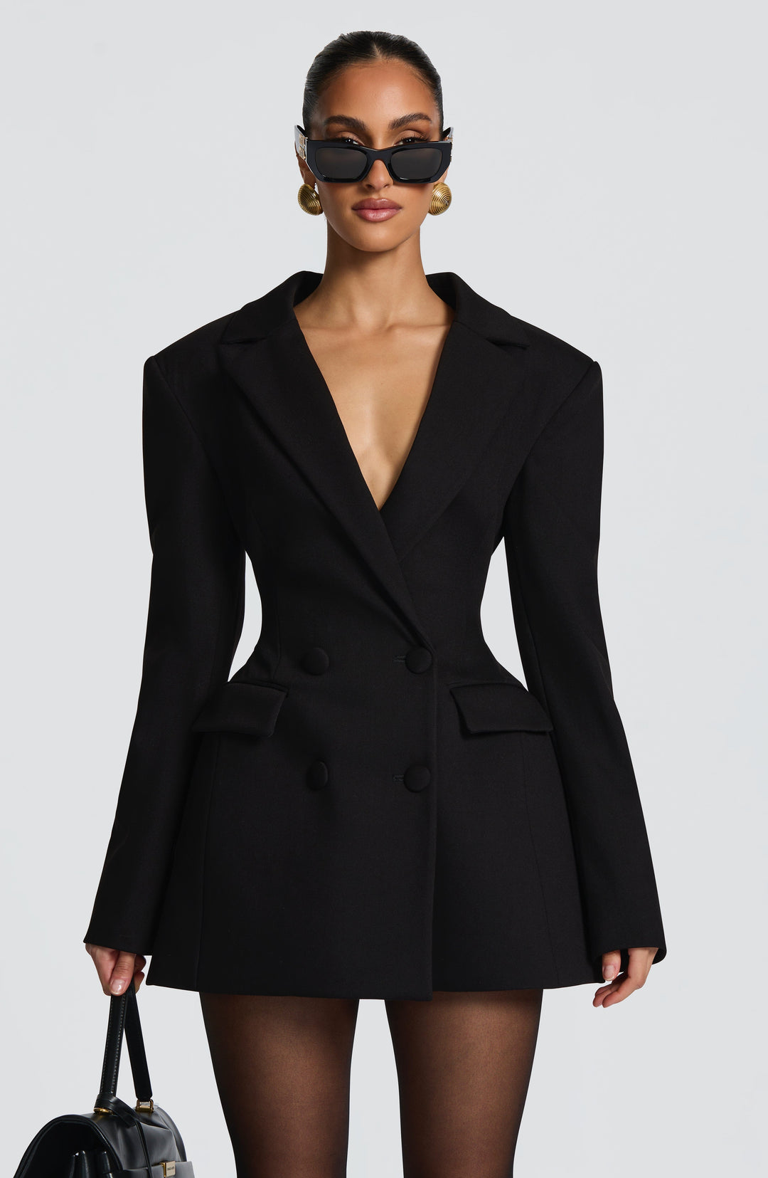 Plan rapproché de la robe blazer noire portée avec lunettes de soleil noires, boutons recouverts de tissu et poches à rabat. 10
