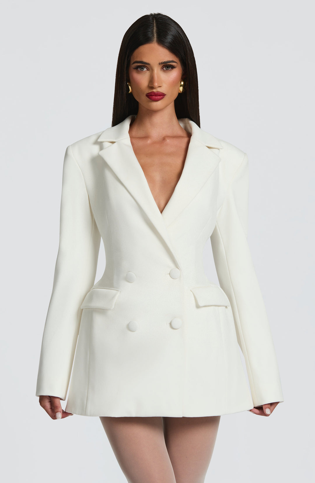 Vue de face rapprochée de la robe blazer blanche portée par une mannequin aux cheveux longs, taille cintrée et épaules marquées. 17