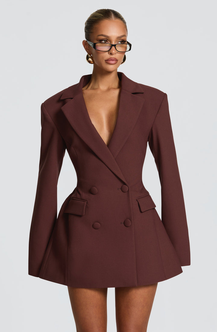 Vue de face rapprochée de la robe blazer marron à double boutonnage, col cranté plongeant, taille cintrée et épaules structurées, portée avec lunettes. 1