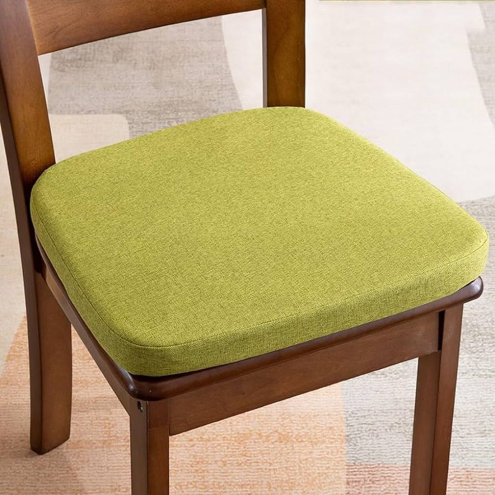 Coussin vert anis aux angles arrondis posé sur une chaise en bois foncé 1