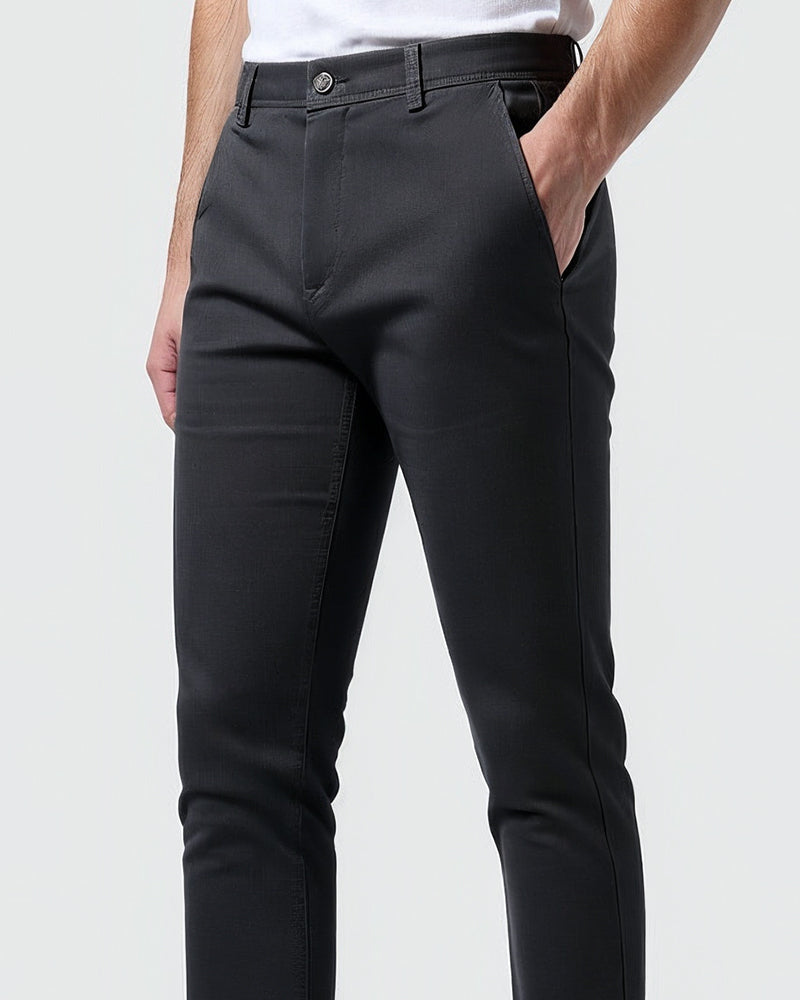 Gros plan sur la taille du chino anthracite, avec une main dans la poche latérale, bouton et passants de ceinture. 10