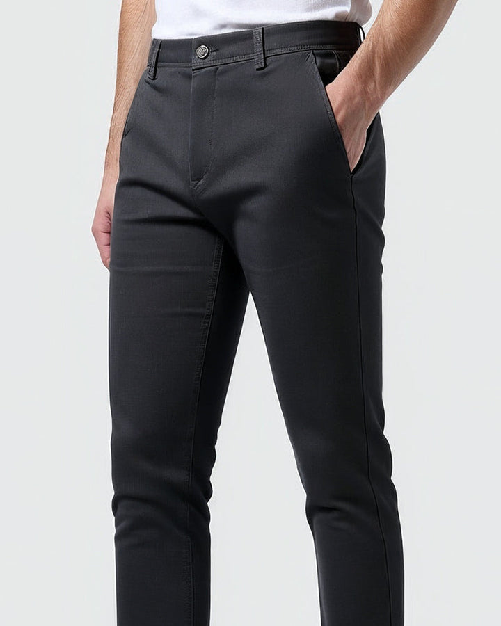 Gros plan sur la taille du chino anthracite, avec une main dans la poche latérale, bouton et passants de ceinture. 10