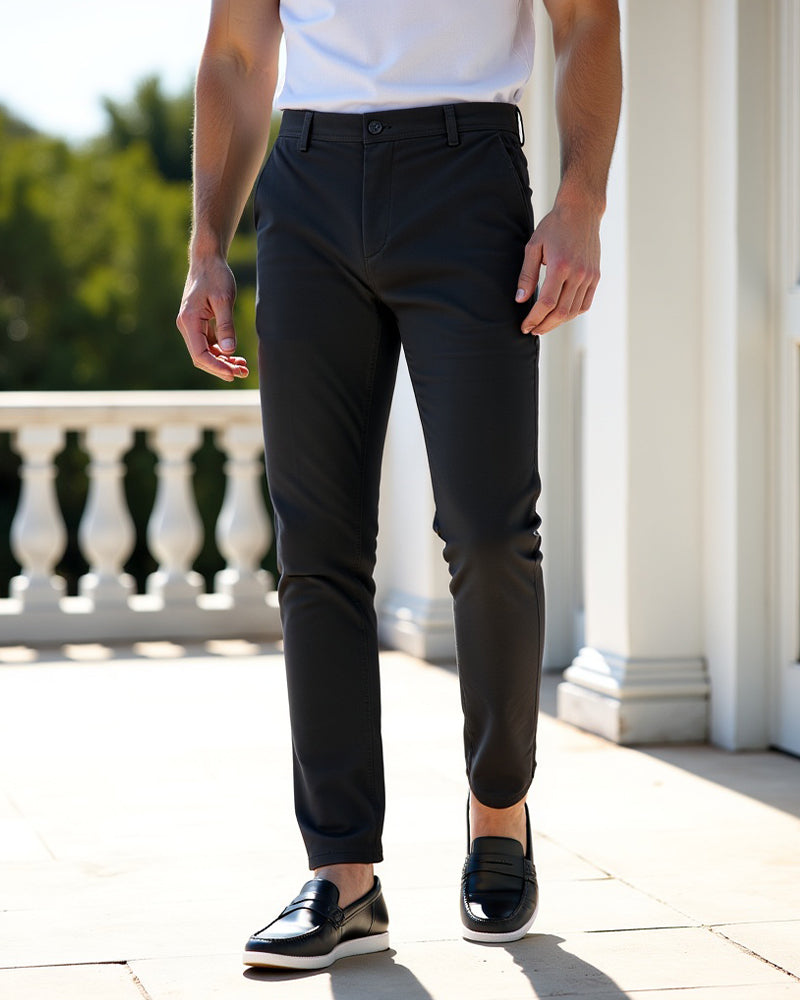 Chino anthracite porté face à une balustrade blanche, avec un t-shirt blanc et des mocassins noirs en cuir. 7