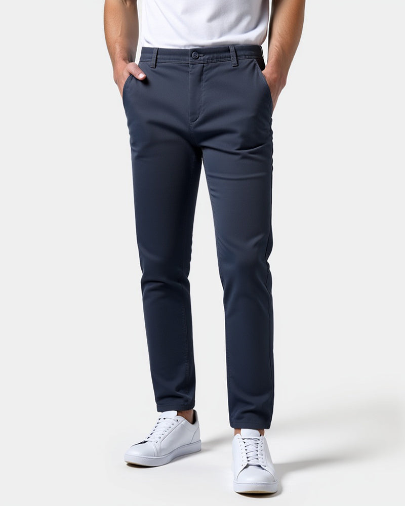 Chino bleu marine porté de face avec un t-shirt blanc, les mains dans les poches et des baskets blanches. 15