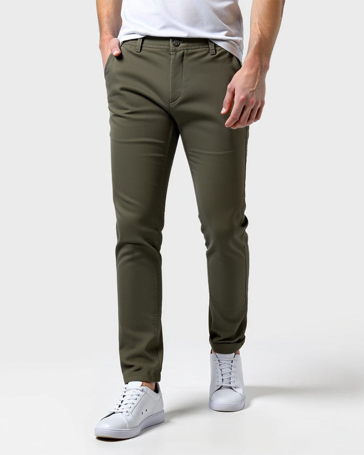 Chino vert kaki porté de face avec un t-shirt blanc, une main dans la poche et des baskets blanches. 13