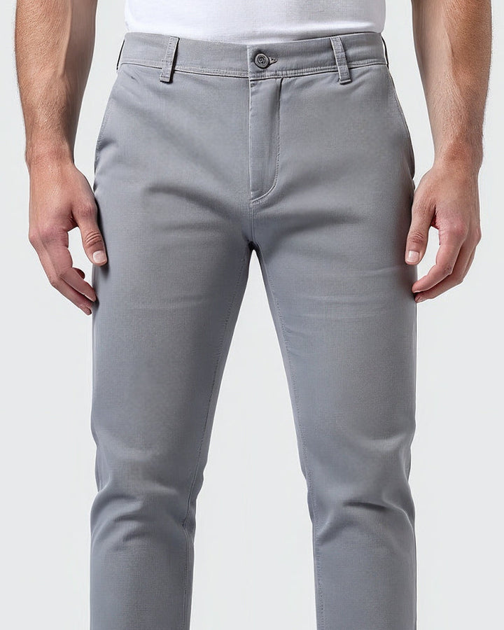 Gros plan sur la taille du chino gris clair : bouton, fermeture sur le devant et passants de ceinture. 5