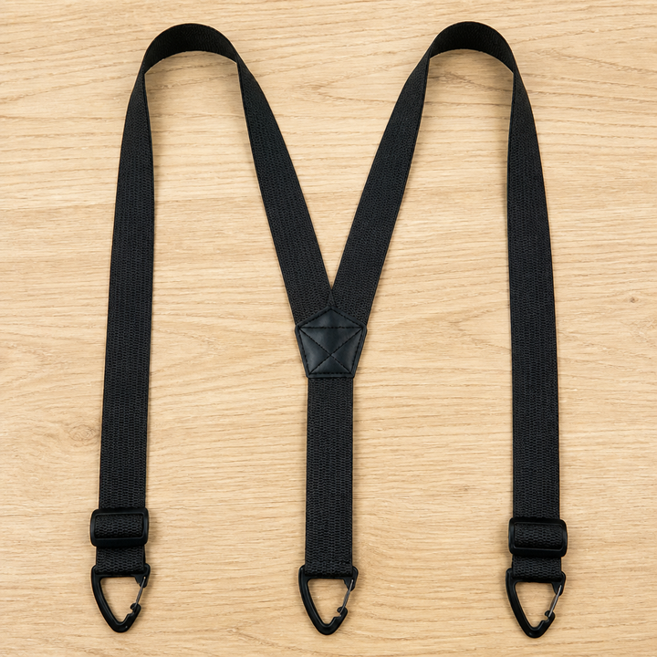 Bretelles noires en Y avec boucles de réglage placées près des crochets triangulaires, posées à plat sur du bois. 13
