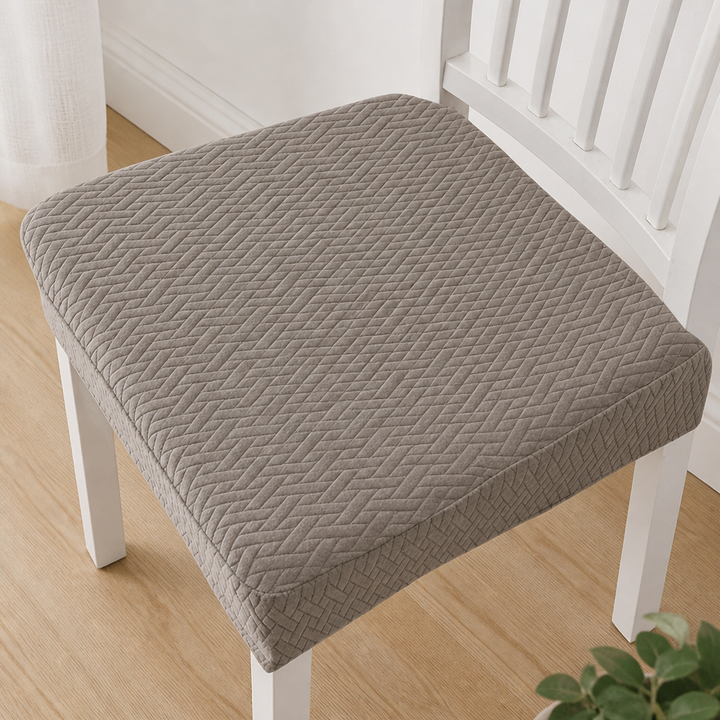Vue de dessus d'une housse d'assise taupe Ă  motif de chevrons en relief sur une chaise blanche. 12