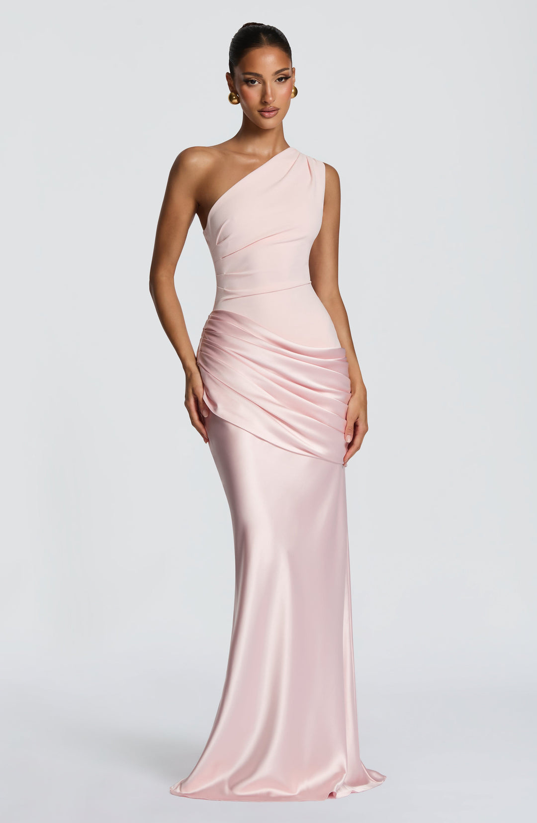 Robe longue rose pâle en position légèrement inclinée, mannequin main sur la hanche, jupe satinée fluide. 12