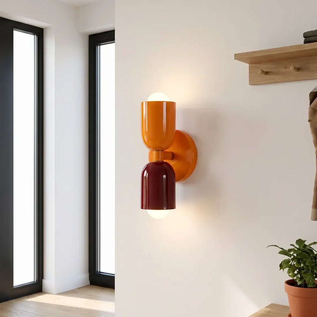 Applique orange vif et bordeaux allumée dans une entrée lumineuse, près d'une étagère à patères en bois. 11