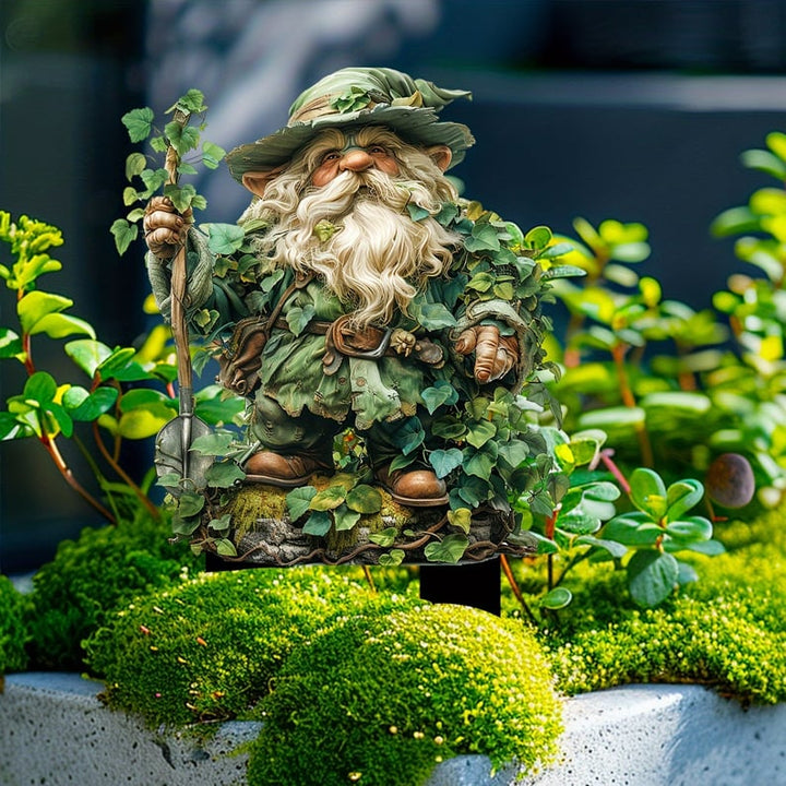Tuteur du gnome barbu à chapeau et pelle, planté dans de la mousse et de petites plantes vertes devant un mur sombre. 13