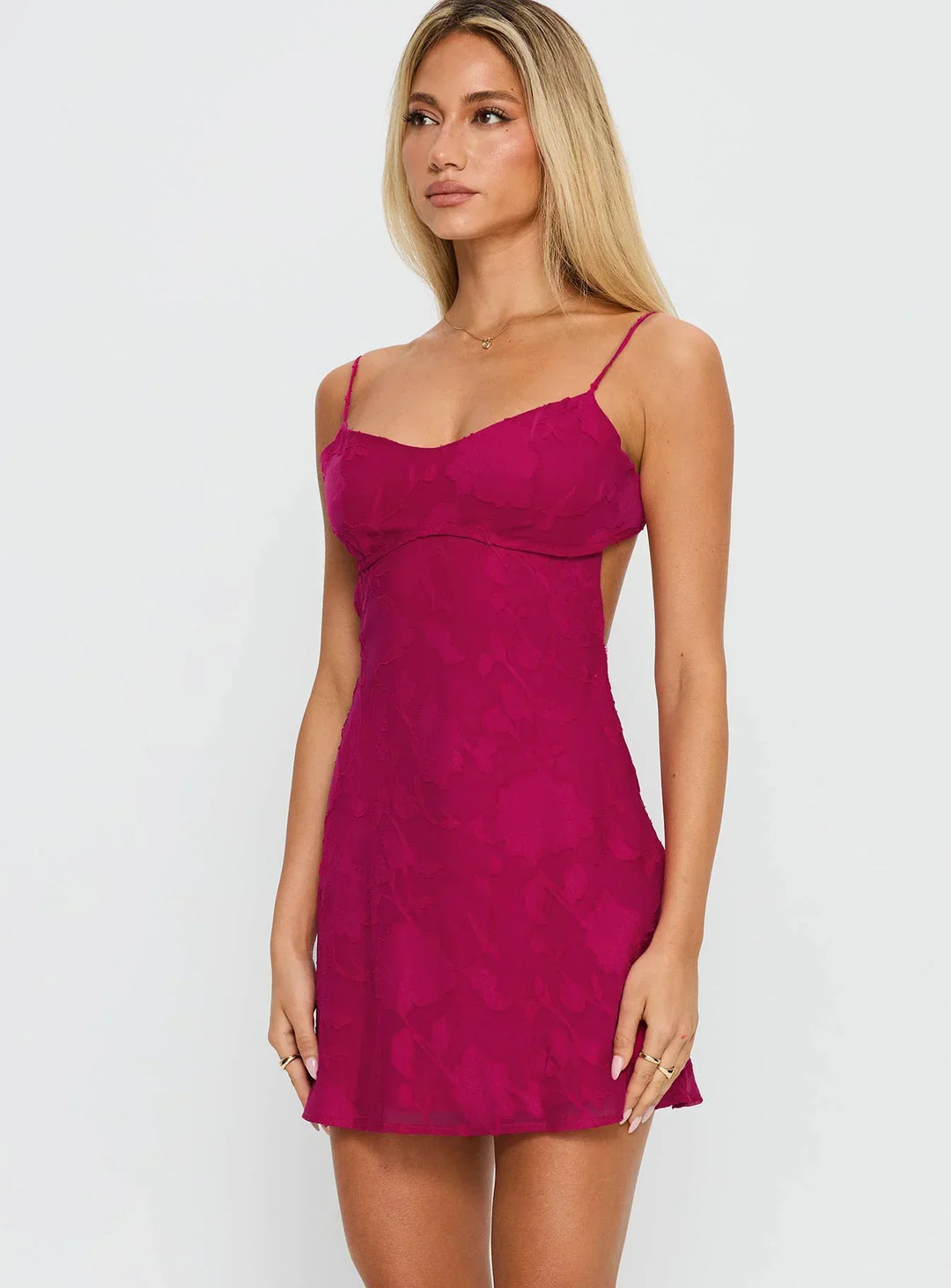 Vue de trois quarts de la robe fuchsia, montrant le bustier, la taille ajustée, le dos ouvert sur le côté et la jupe évasée. 7