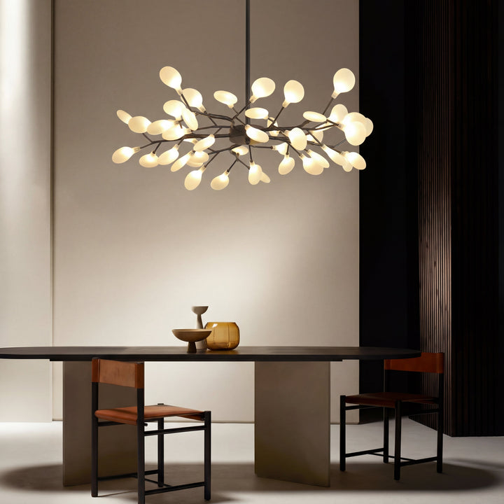 Lustre à branches allumé au-dessus d'une table ovale sombre, intérieur épuré aux tons neutres 5