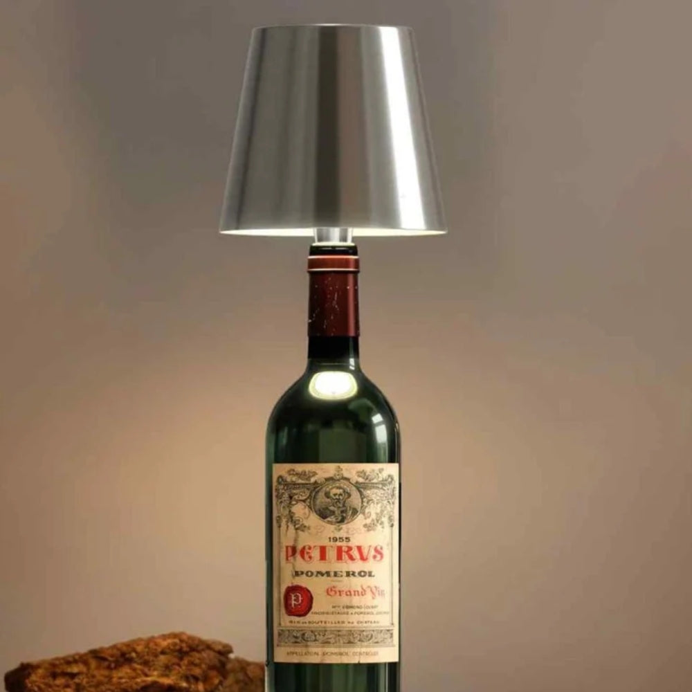Abat-jour argenté posé sur une bouteille de vin rouge ancienne, en gros plan sur fond beige 15