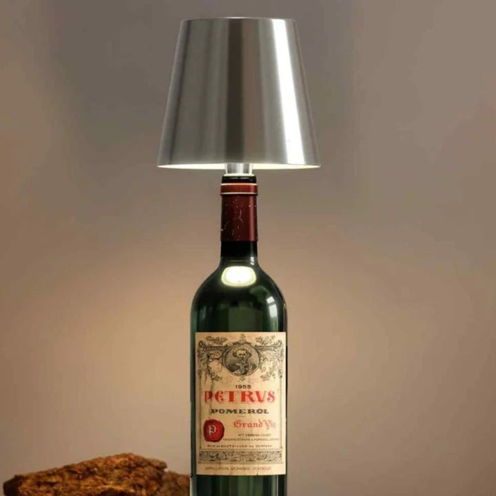 Abat-jour argenté posé sur une bouteille de vin rouge ancienne, en gros plan sur fond beige 15