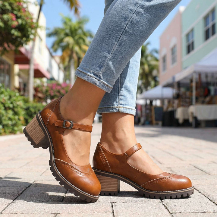 Mary Janes marron portées en ville sur un pavé ensoleillé, avec jean clair, profil montrant talon bloc et boucle de bride. 5