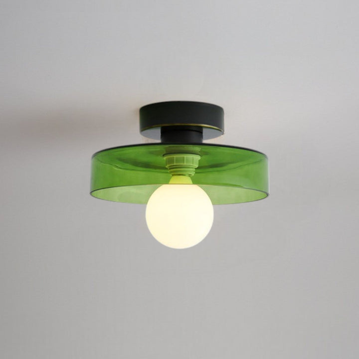 Plafonnier à abat-jour en verre vert et base noire, douille verte visible, ampoule globe opaline allumée. 9