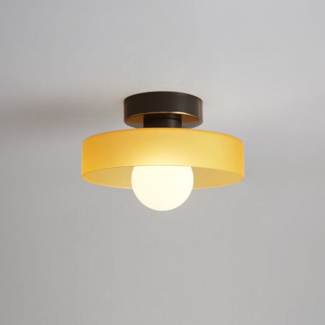 Plafonnier à abat-jour jaune ambré et base noire à liseré doré, avec ampoule globe allumée, fixé au plafond. 10