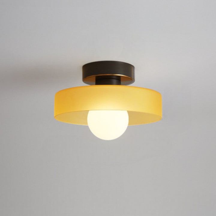 Plafonnier à abat-jour jaune ambré et base noire à liseré doré, avec ampoule globe allumée, fixé au plafond. 10