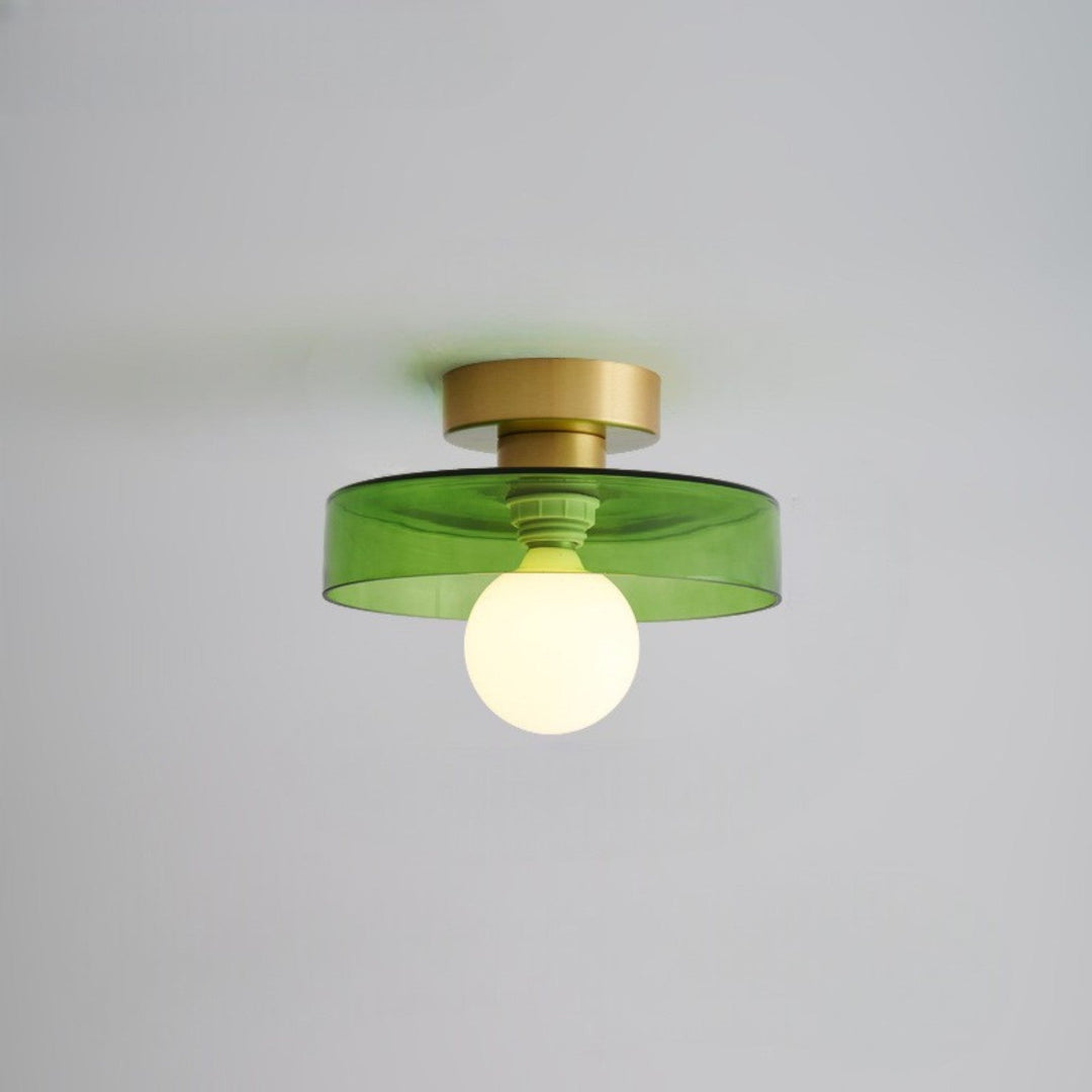 Plafonnier à abat-jour en verre vert transparent et base dorée, douille verte visible, ampoule globe opaline allumée. 14