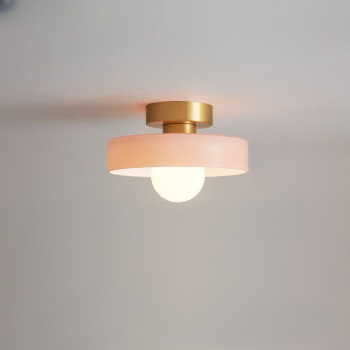 Plafonnier à abat-jour rose pâle et base dorée, avec ampoule globe allumée, fixé au plafond. 13