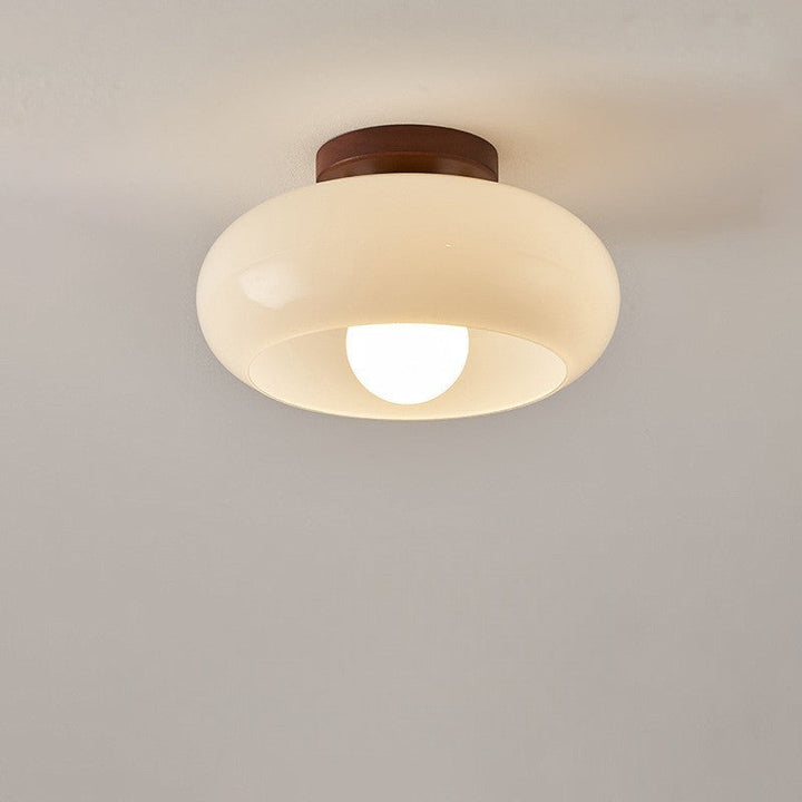 Plafonnier en verre arrondi allumé, vu de face sur un plafond uni, avec ampoule ronde 6