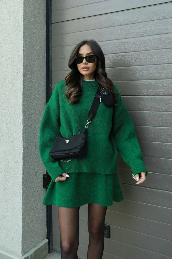 Ensemble vert en maille porté avec un sac bandoulière noir et des lunettes de soleil, devant un portail gris. 8