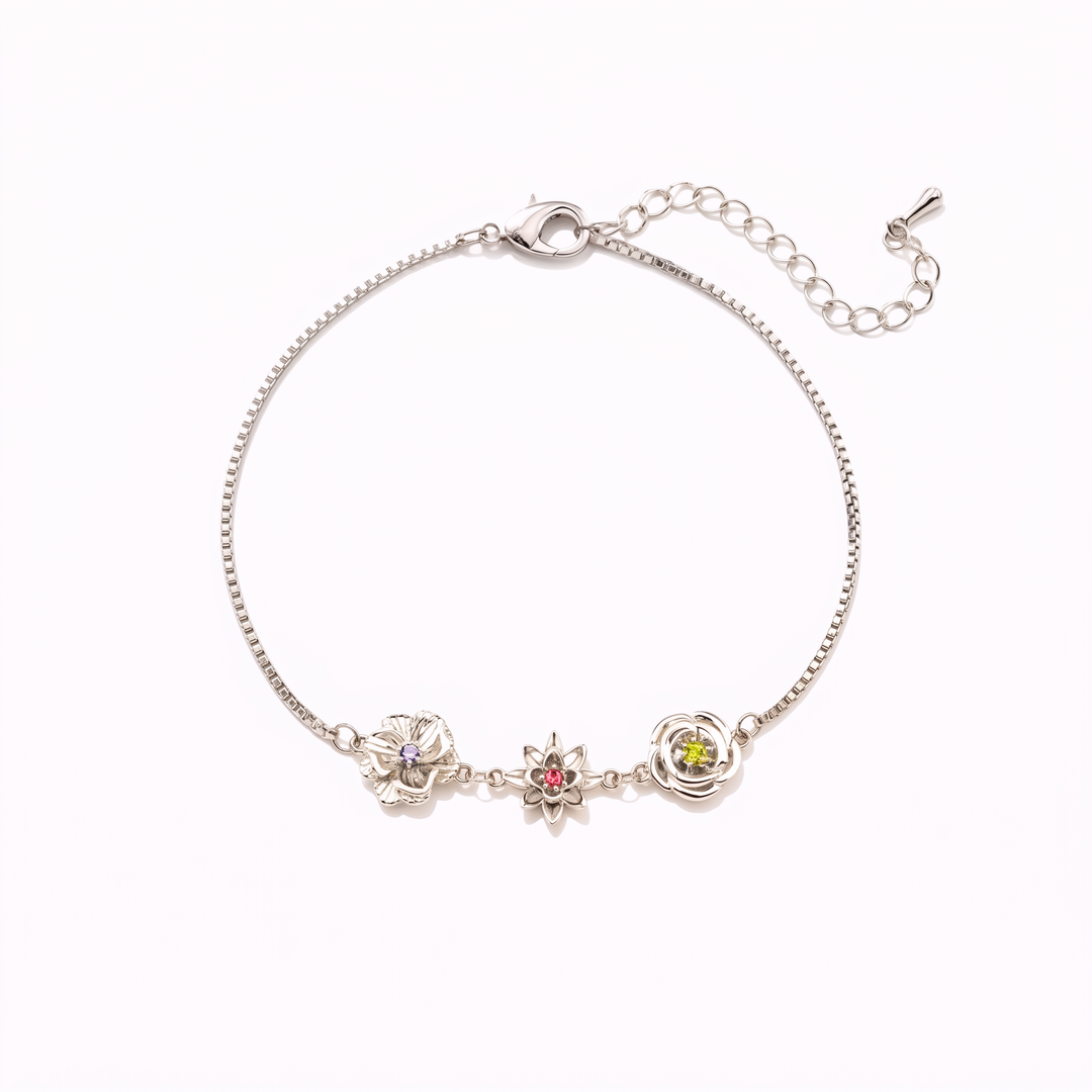 Bracelet argenté vu à plat sur fond blanc, avec trois fleurs serties de pierres violette, rouge et verte et sa chaînette de rallonge. 16