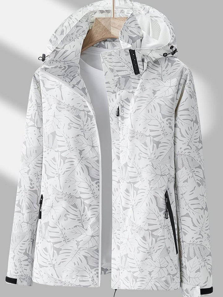 Veste blanche et gris clair à imprimé de feuilles, capuche ajustable, poches zippées noires, présentée ouverte sur un t-shirt blanc. 3