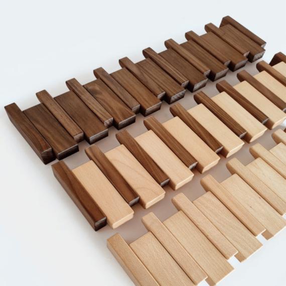 Pièces de bois en vrac posées à plat, rangées en lignes de teintes foncée, moyenne et claire 8